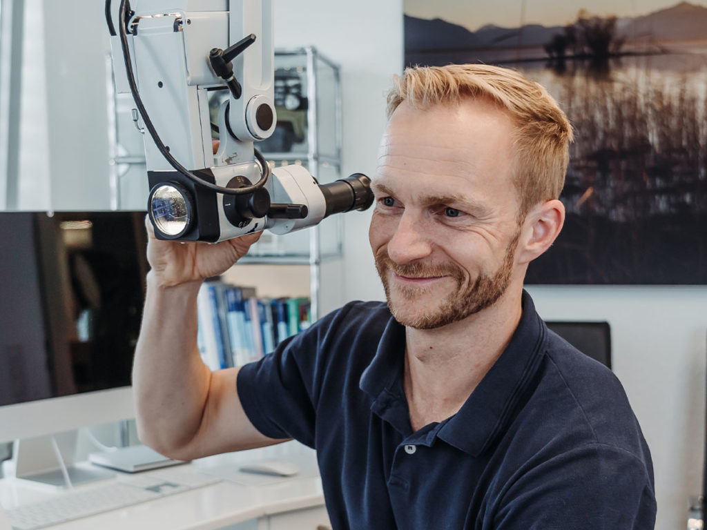 Dr. Bernhardt freundlich guckend am Behandlungsmikroskop